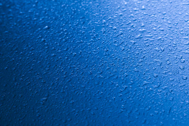 Water drops on the car surface.  Rainwater drops onto the surface of the car. Blue, black, green. Gradation from dark to light.
