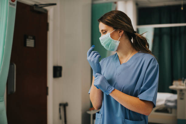 istock Female nurse with a mask putting on gloves 2157511208