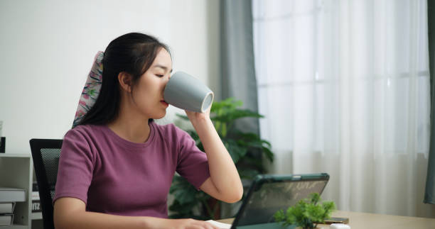 istock Business woman drinking coffee while using digital tablet at home 2157513413