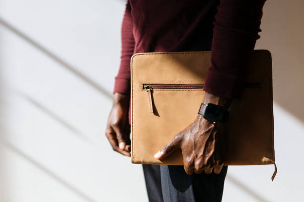 Man with a wristwatch holding a brown briefcase