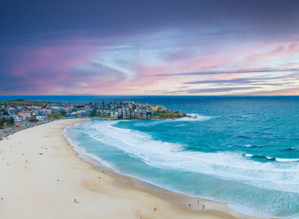 Capture the essence of summer with an aerial view of people relaxing on Bondi Beach, Sydney, under a dramatic afternoon sky, enjoying the sun and surf.