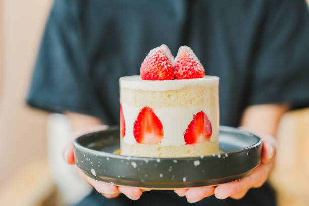 istock A woman's hand is holding a strawberry shortcake. 2157517934