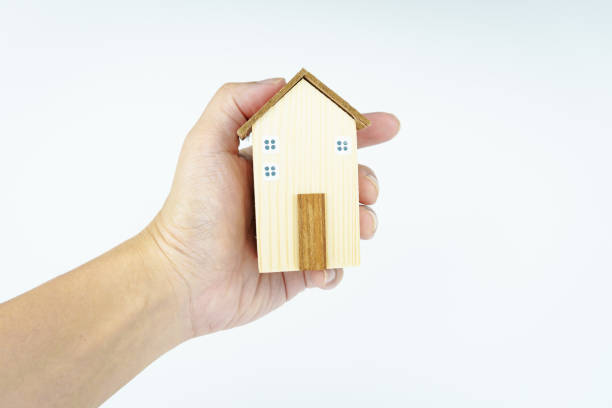 istock hand holding small wooden house on white background. 2157518070