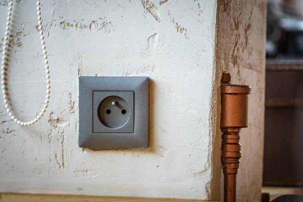 A white electrical socket installed on a pastel blue wall, simplistic design.