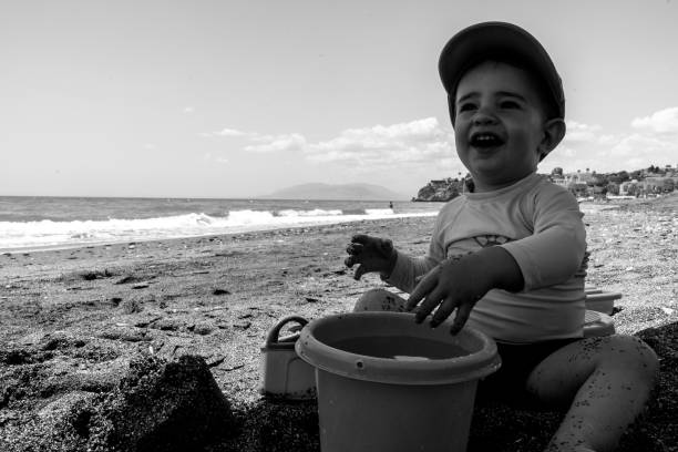 Little boy aged 8 filling his bucket with water. Sunny summer day in Tuscany, Italy.\n