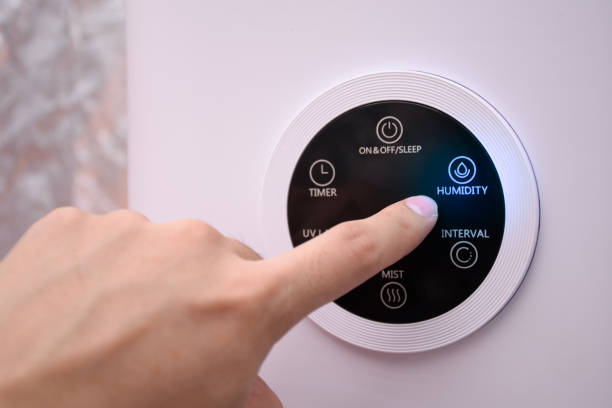 Close up man hand pressing the digital humidifier button on a smart humidifier in a smart home or green house.