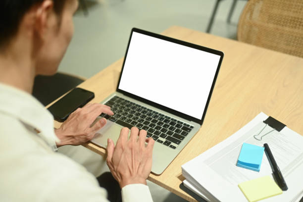 istock Over shoulder view of young businessman working with laptop on table at office 2157541018