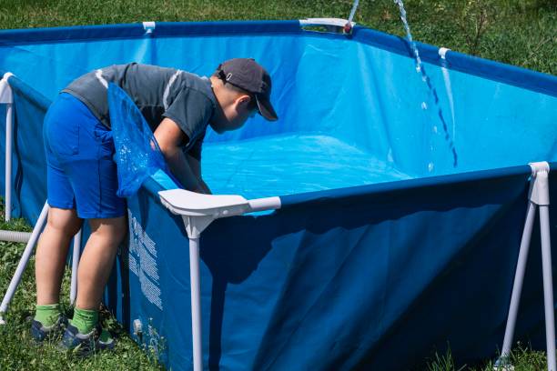 istock Boy actively involved in removing impurities from a pool, ensuring the water remains pure and reflective 2157541409