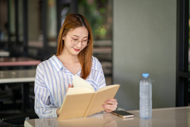 istock Young woman reading a book while waiting for food 2157543417