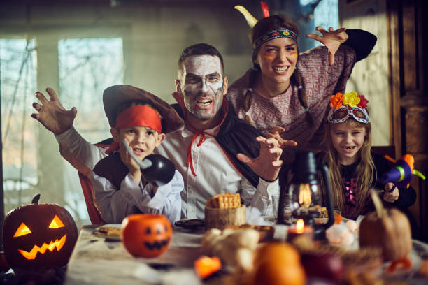 happy family in halloween costumes having fun at dining table. - decoration halloween photos et images de collection