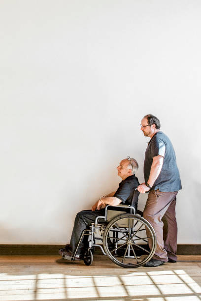 istock Man pushing his dad's wheelchair 2157545753