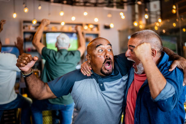 Senior fans men celebrating a goal on sports match on the bar Senior fans men celebrating a goal on sports match on the bar excited football fan cheering for his team on tv stock pictures, royalty-free photos & images
