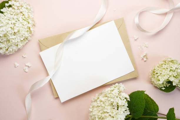 istock Blank wedding invitation or greeting card mockup with white hydrangea flowers on a beige background. Flat lay, top view, copy space. 2157553488