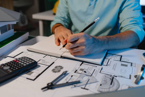 istock The architect is working on blueprint of important project by using his creativity, the engineer drafts and uses construction design equipment, full of design paperwork on the architect's desk 2157554989