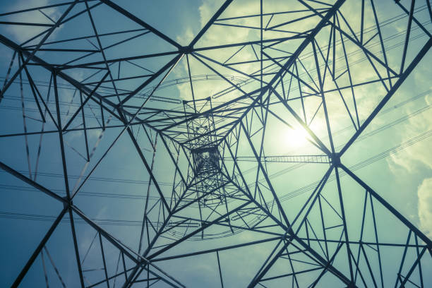 Abstract pattern from bottom view of high voltage pole power transmission tower with backlit sunshine sky background in monochrome. Green energy saving, electrical technology, abstract pattern concept