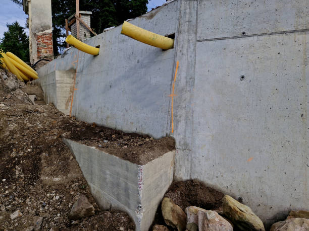 istock long straight supporting wall of cast cement mixer formwork. behind wall is soil that is brought out through the wall by drainage pipes. sewer pipe drain in line. construction site, white, field 2157557450