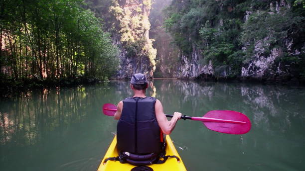 istock Traveler rows with paddle navigating kayak in canyon 2157561439