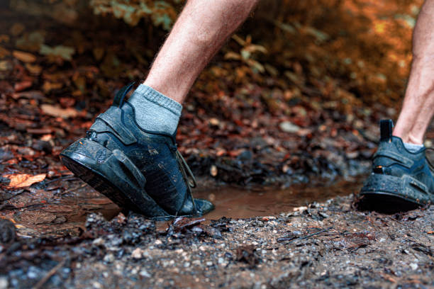 istock Runner stepping into the muddy trail puddle 2157563828