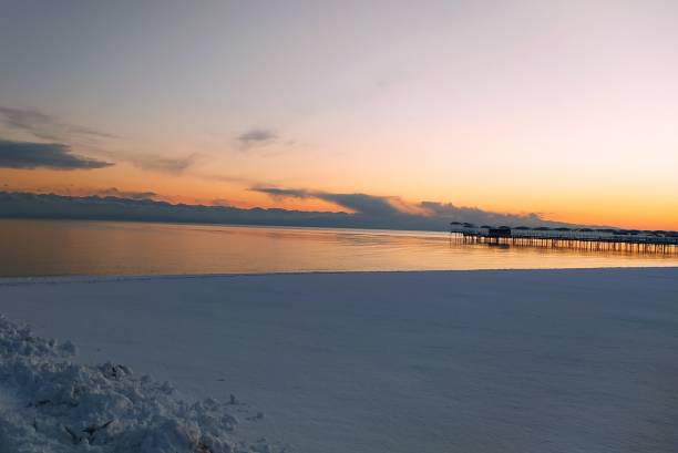 Female tourist is walking on Issyk-Kul lake shore on a cold sunny winter morning and streaming by wearable camera