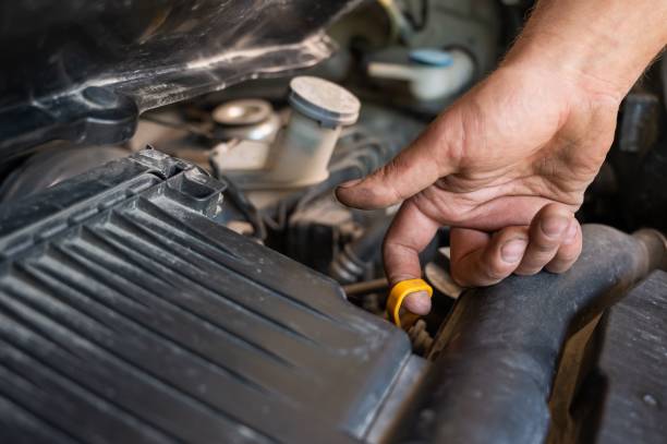 istock An auto mechanic pulls out a dipstick to check the oil level in a car engine. 2157573548