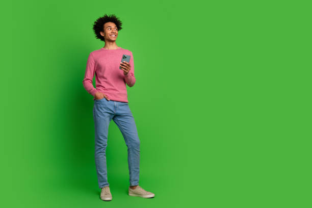 istock Full length photo of cheerful positive guy dressed pink pullover reading modern gadget emtpy space isolated green color background 2157573780