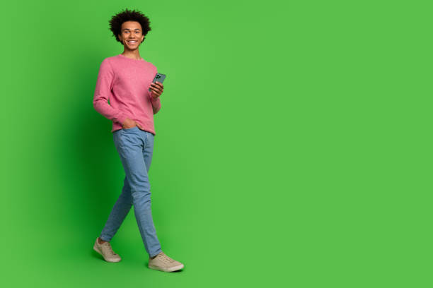 istock Full length photo of funky cool guy dressed pink pullover typing modern gadget walking emtpy space isolated green color background 2157573805