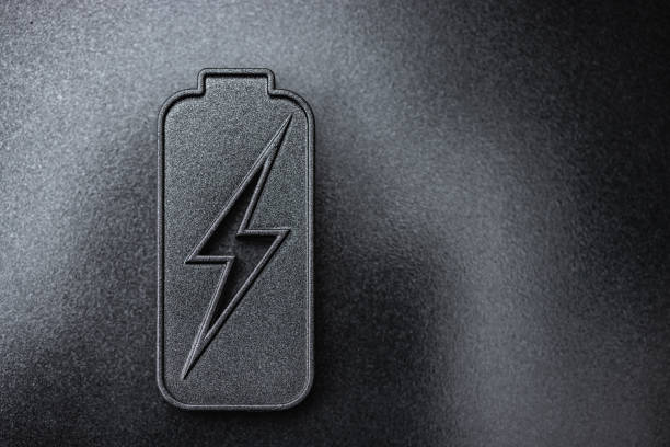 Energy concept. Battery energy technology background. Charged battery icon representing innovative power technologies and sustainability on dark background. Minimalistic setup with copy space. Elements painted with dark graphite metallic paint