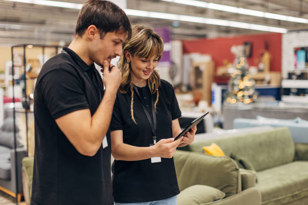 istock Two carefree salespeople in matching outfits use a digital tablet while working in a department store 2157581047