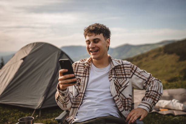istock Young boy sit in front tent and use mobile phone on the mountain 2157581187