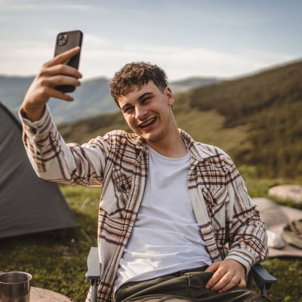 istock Young boy sit in front tent have video call or selfie on the mountain 2157581264