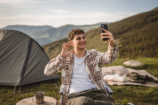 istock Young boy sit in front tent have video call or selfie on the mountain 2157581265