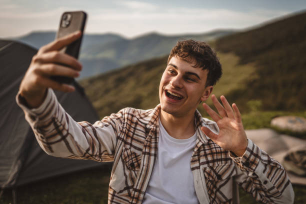 istock Young boy sit in front tent have video call or selfie on the mountain 2157581284