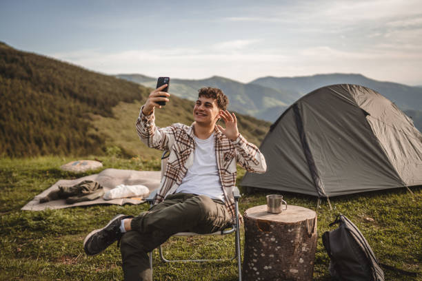 istock Young boy sit in front tent have video call or selfie on the mountain 2157581375