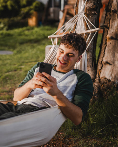 istock Young boy lying down in hammock and use mobile phone on the mountain 2157581418