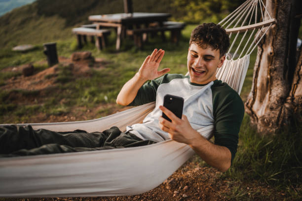 istock Boy lying down in hammock take a self portrait or video call on phone 2157581440