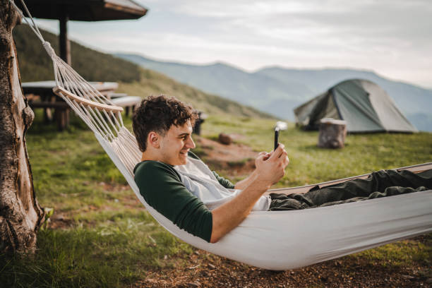 istock Young boy lying down in hammock and use mobile phone on the mountain 2157581463