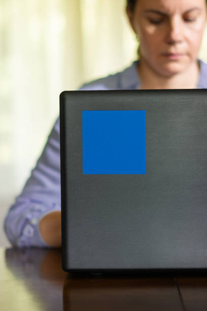 Close-up of blue sticky note on laptop whit serious woman in background
