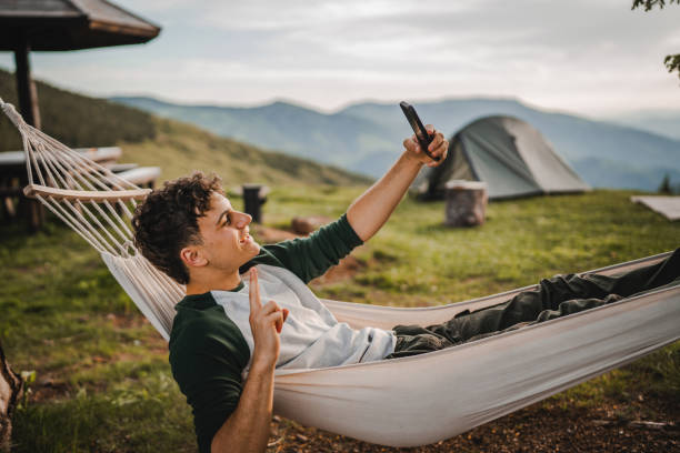 istock Boy lying down in hammock take a self portrait or video call on phone 2157581780