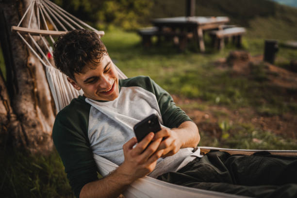 istock Young boy lying down in hammock and use mobile phone on the mountain 2157581807