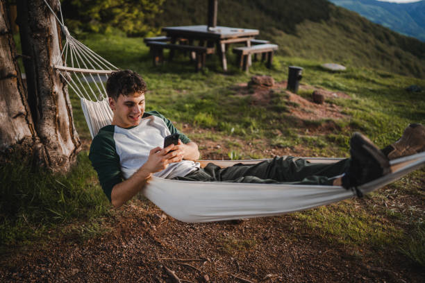istock Young boy lying down in hammock and use mobile phone on the mountain 2157581809