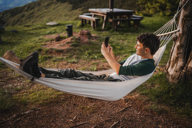 istock Young boy lying down in hammock take picture with mobile phone camera 2157581814