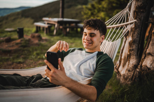 istock Boy lying down in hammock take a self portrait or video call on phone 2157581827