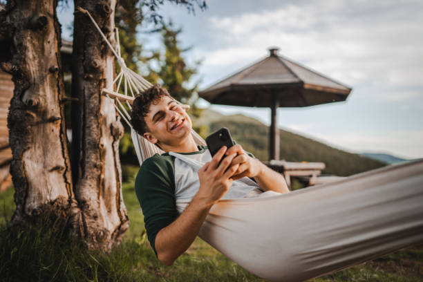 istock Young boy lying down in hammock and use mobile phone on the mountain 2157581853