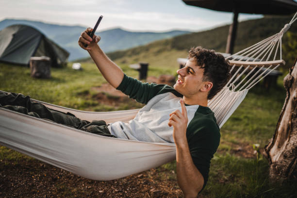 istock Boy lying down in hammock take a self portrait or video call on phone 2157581855