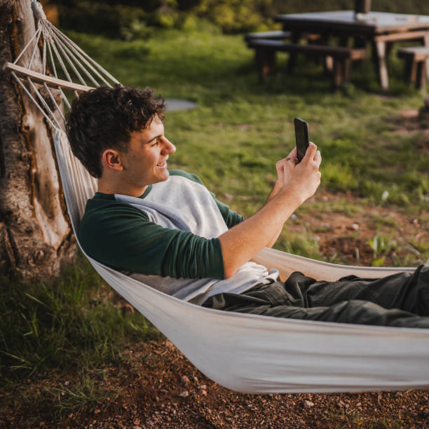 istock Young boy lying down in hammock take picture with mobile phone camera 2157581867