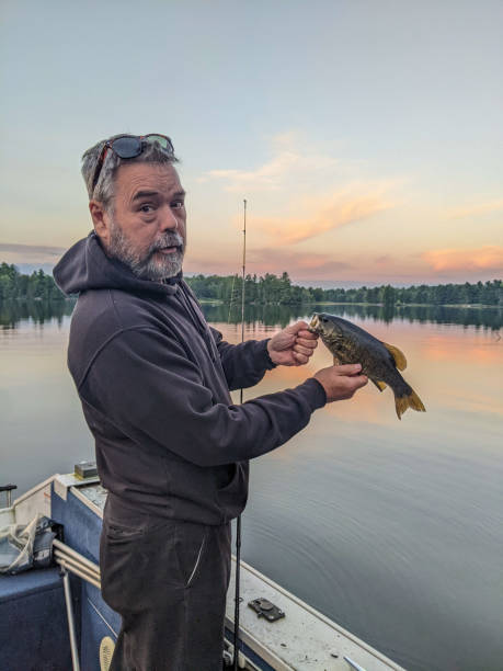 A man holds a smallmouth bass on a boat
