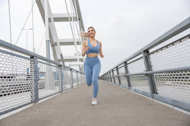 istock sporty young woman running over bridge 2157584144