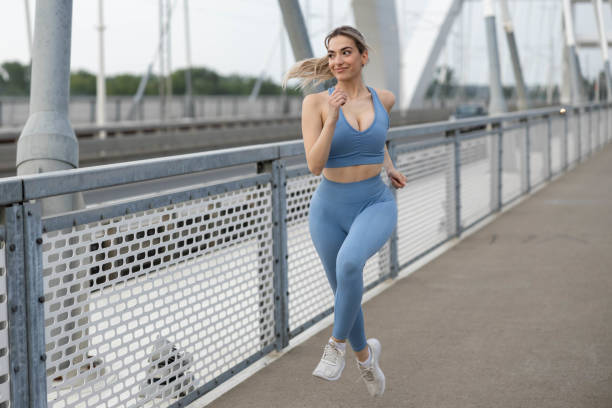 istock sporty young woman running over bridge 2157584164