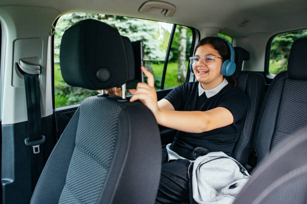 istock Caucasian schoolgirl, using a digital tablet connected to a car WiFi, while sitting in the backseat 2157586024