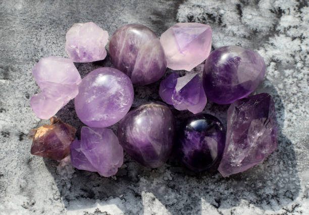 istock Beautiful natural amethyst crystals illuminated by sunlight on a gray background. Healing crystals. 2157586146